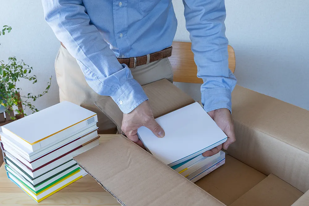 Mann verstaut Bücher im Umzugskarton Mann verstaut Bücher im Umzugskarton